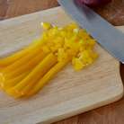 Затем разрезать пополам и удалить семена у сладкого перца (красного и желтого), нарезать полосками и также на маленькие кубики. Стараемся нарезать все овощи одинаково размера.