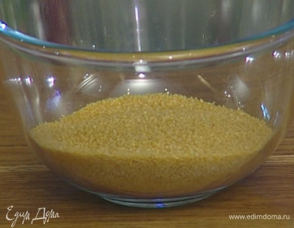 Кускус высыпать в глубокую посуду, залить 1 стаканом воды и поставить на 1 минуту в микроволновку. Затем размять вилкой и снова поставить на 1 минуту в микроволновку.