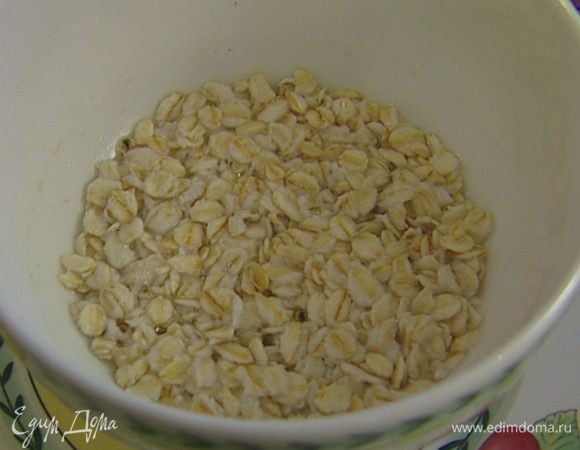 Овсяные хлопья залить небольшим количеством кипятка так, чтобы они были слегка покрыты водой, и оставить набухать.
