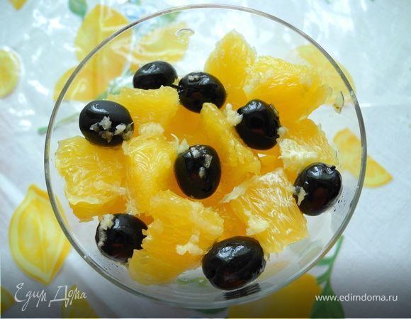 Апельсин разделить на дольки, освободить от пленок, нарезать на крупные кусочки, добавить оливки, измельченный чеснок. Заправить оливковым маслом. Если любите - можно посыпать кунжутом.