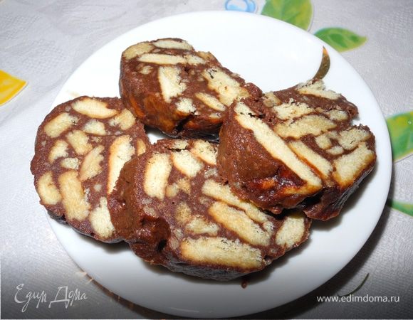 Растопить на очень маленьком огне сливочное масло, добавить сахар, какао, хорошо размешать, добавить яйцо, энергично перемешать, чтобы получилась эластичная однородная масса (если будут есть только взрослые можно добавить 1 ст. ложку коньяка). Добавить в эту смесь поломанное на кусочки печенье, все хорошенько перемешать, сформировать из этой массы колбаску, завернуть ее в пергаментную бумагу и положить в морозилку на 1-2 часа, можно больше. Когда застынет - разрезать на кусочки. Выглядит очень оригинально и очень вкусно.