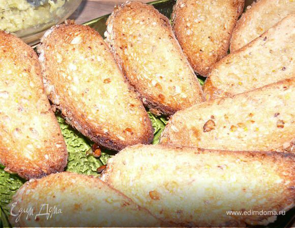 Порезать багет тонко наискосок, сбрызнуть ломтики оливковым маслом, поставить запекать в духовку на сухом противне 10-15 минут.180 градусов до золотистого цвета.Готовые теплые ломтики натереть долькой чеснока.