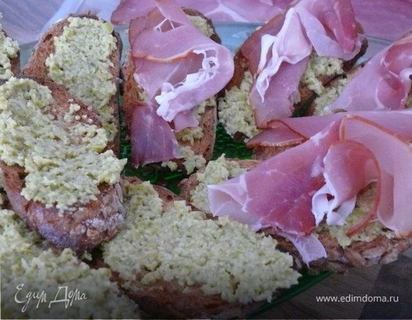 Пюрировать оливки блендером, не добавляя больше никаких ингредиентов. Намазать получившиеся кростини. Сверху - ломтик пармской ветчины.