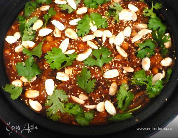 Выложить на блюдо (если готовите в тажине, подавайте прямо в нем). Посыпать миндальными хлопьями,  кунжутными семенами и листьями кинзы. В качестве гарнира хорош кус-кус, простой или с небольший количеством специй.
