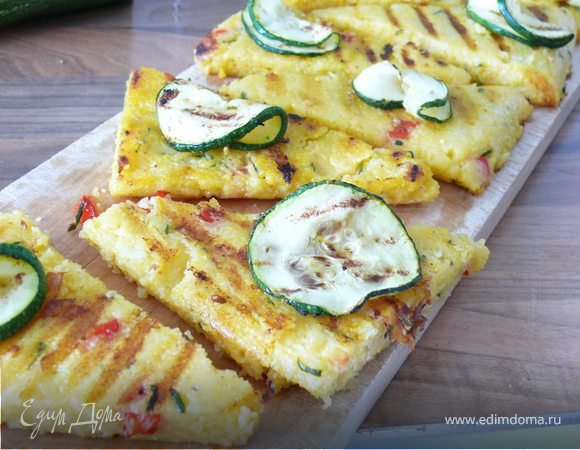 Сильно разогреть сковороду-гриль. Нарезать поленту на куски, смазать оливковым маслом и обжарить кусочки с 2-х сторон до золотистого цвета. Можно запечь так же под грилем.Украсть обжаренными на гриле ломтиками кабачка( по желанию)