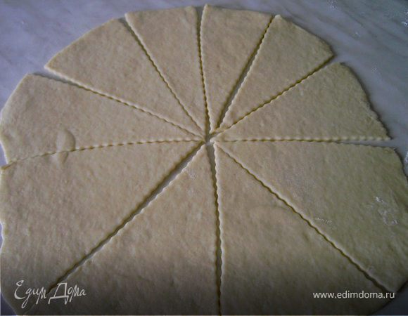 Готовое тесто разделить на 2-3 части.Каждую часть раскатать толщиной 2-3мм на хорошо посыпанной мукой поверхности.Лепёшку разрезать на треугольники.