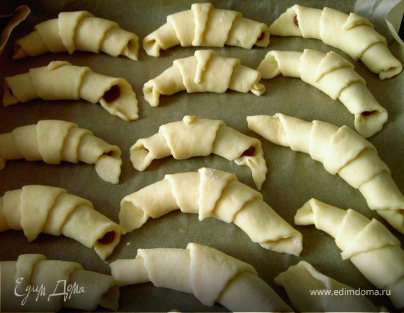 Скрутить треугольники,начиная от широкой стороны,и уложить на смазанный или выстеленный бумагой для выпечки противень.