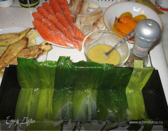 У порея отрезать белую часть, оставив с зелеными листьями см.5-7 белой части. Зеленые листья надрезать от основания до сердцевины, чтобы получились прямоугольные пласты, промыть от песка, бланшировать крупные листья в подсоленном кипятке 3-5 минут. Откинуть на дуршлаг и слегка обсушить. 
Выложить подготовленные листья внахлест в смазанную форму так, чтобы они свисали по краям.