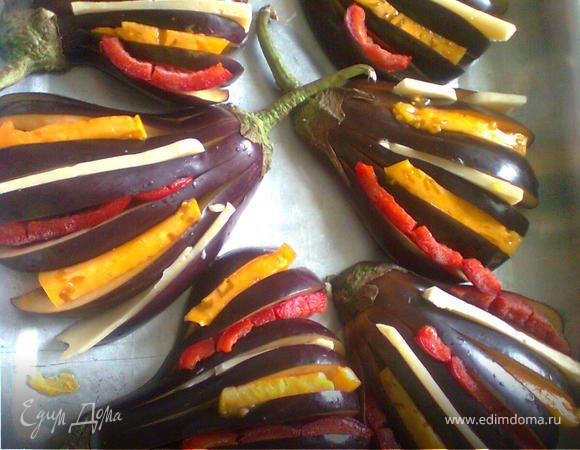 Выложить подготовленные половинки баклажанов в смазанную маслом форму или на противень.
Нашпиговать баклажаны, вклaдывaя в разрезы бекон (не ложила), помидоры, перец и сыр.