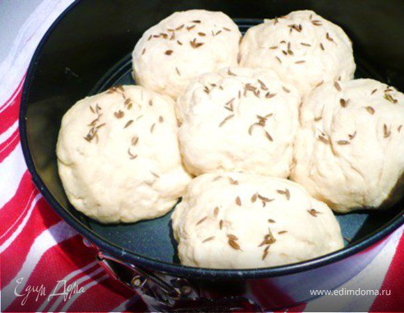Подбить тесто 1 минуту. Сформировать 6 шариков и положить в смазаную маслом форму диаметром ок. 21 см. 5 шариков по бокам и один в середине. Посыпать тмином и/или мукой(или без муки). Накрыть полотенцем и поставить в теплое место , пока тесто не увеличится в 2 раза .
