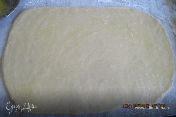 Переложите тесто на доску и раскатайте в прямоугольник 50x30см. Смажьте тесто растопленным маслом.