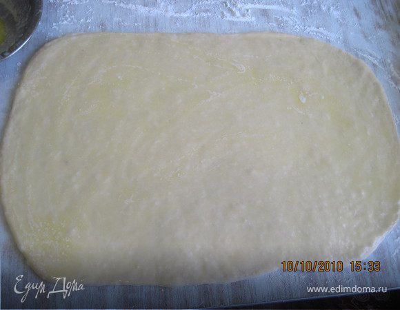 Переложите тесто на доску и раскатайте в прямоугольник 50x30см. Смажьте тесто растопленным маслом.