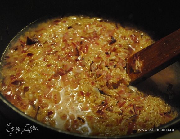 В кастрюле обжарить лук на оливковом масле, добавить рис и влить 2 половника горячего бульона. Подождать, когда жидкость впитается, и продолжать постепенно вливать бульон, не забывая помешивать.