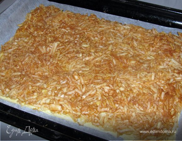 Тесто тонко раскатать и выложить на противень, застеленный пергаментом.
Выложить натертые яблоки. Посыпать корицей.