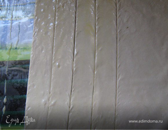 Из теста раскатать прямоугольник со стороной 25см, толщиной 3 мм. Разрезать его на полоски шириной 2,5 см и длиной 25 см. Растереть желток с водой. Смазать полоски.