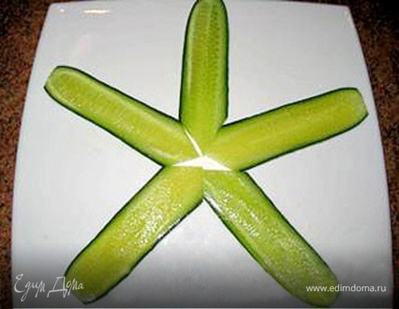 Огурцы тонко разрезать вдоль и выложить основу салата.