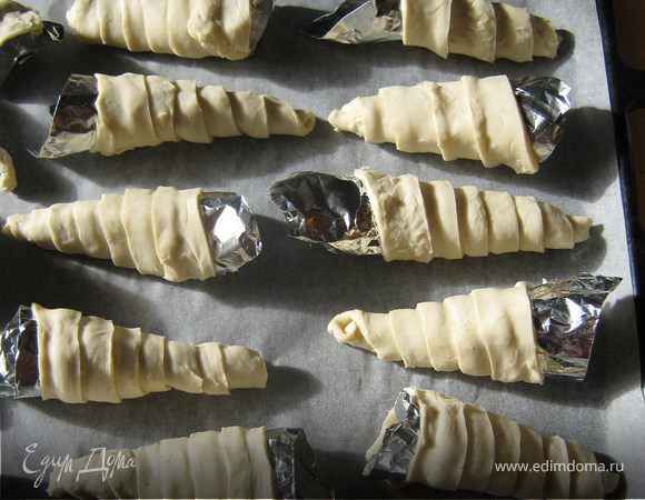 Накрутить полоски теста смазанной стороной вверх на формочки из фольги по спирали внахлёст. Выложить на противень.