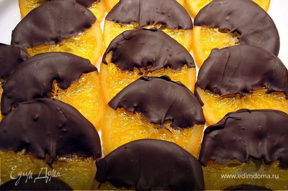 Шоколад растопить на водяной бане, апельсиновые кружки окунуть до половины в растопленный шоколад, уложить на пекарскую бумагу