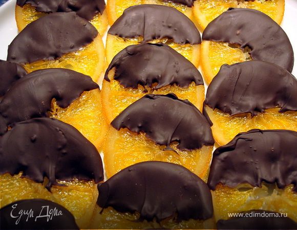 Шоколад растопить на водяной бане, апельсиновые кружки окунуть до половины в растопленный шоколад, уложить на пекарскую бумагу 