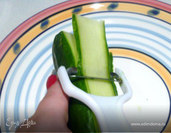 Огурцы нарезать овощечисткой полосками. Но не захватывать  семена. Поставить нарезанные огурцы в холодильник на 10 минут.

