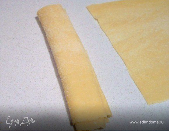 Пересыпая каждый раз мукой, сложить в три раза,в трубочку.