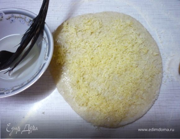 Для сырного багета "Сырная палочка" большую часть сыра (60 г) трем на мелкой терке. Раскатываем тесто как для классического багета, но на тех этапах где мы смазываем тесто маслом, еще и посыпаем тесто мелко натертым сыром и раскатываем как обычно. Верх багета смазываем водой, а не маслом и посыпаем тертым на крупной терке сыром. Делаем два длинных продольных надреза на 1/3 глубины багета вдоль и оставляем расстаиваться минут на 20. 