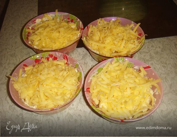 Разложить жульен по кокотницам. Залить сливочным соусом так, чтобы соус не покрывал курицу полностью.
Обильно посыпать сверху тёртым сыром.
Поставить кокотницы в нагретую до 200°С духовку на 10 минут