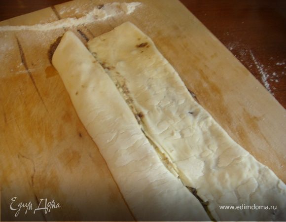 Разложить пласт теста на столе. Выложить на тесто ровным слоем половину получившейся смеси. Завернуть тесто с двух сторон, конец к концу. Еще раз завернуть тесто, потом сложить пополам так, чтобы получилось 8 слоев. 