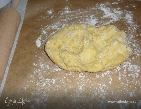 К картошке добавить 2 яйчных желтка, муку и мускатноый орех. Тщательно перемешать. Картофельное тесто выложить на посыпанную мукой бумагу для запекания или пленку.