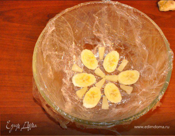 Берем миску формы будущего тортика. Чуть смазываем растительным маслом и выкладываем дно пищевой пленкой. Дно украшаем фруктами.