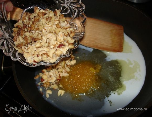 Для карамели распустить в сковороде сливочное масло, добавить, помешивая, сахар, мёд, орехи и молоко. Я предпочитаю крупно рубленный фундук, у него выразительный, очень подходящий вкус, а вот тонкие миндальные листочки за время выпечки могут, думаю, обгореть. Довести до кипения и залить смесью яблоки.