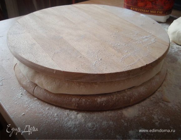 вторую доску посыпаем мукой и накрываем  пирог, переворачиваем, снимаем доску и разминаем пирог ровнее.