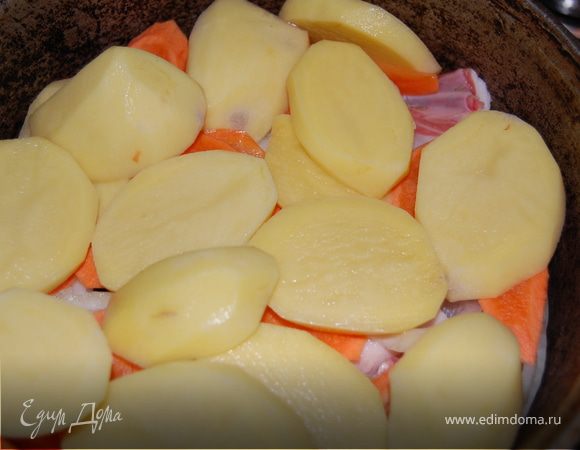 Далее кладем слоями лук полукольцами, потом если есть, то помидоры. Важно – помидоры не должны контачить с картофелем, между ними кладем морковь, иначе картофель станет твердой, как стекло! Но у меня помидоров не было и я кладу на лук морковь крупными кольцами, затем картофель, затем яблоки без сердцевинок, порезанные на 4 части, перец сладкий кольцами. Солим и посыпаем зирой еще разок, кладем зелень, можно порубить, но лучше целиком, чтоб потом проще было ее вынуть. Чеснок мы не рубим, а только чистим, острый перец кладем целиком, ни в коем случае не надрезаем его!