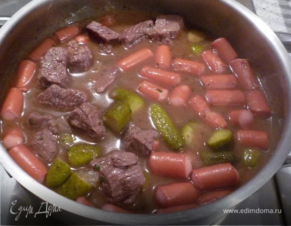 Сосиски добавить к мясу за 5 минут до окончания времени тушения. Затем 
добавить соленые огурцы и петрушку.
