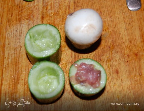 Займемся огурцами. Режем огурцы. У меня были средней длинны, я их порезала на 4 части. Срезала «пупки», острым ножиком и чайной ложкой наделала «дупла», куда будем укладывать наш фарш. Должны получиться «стаканчики» . Очень аккуратно надо выковыривать серединку с семенами, чтоб не продырявить огурец насквозь. Чем крупнее огурец – тем проще. Начиняем огурцы, сверху закрываем наши отверстия шампиньончиками. Если у грибов длинные ножки – укоротите их, но полностью не срезайте. 