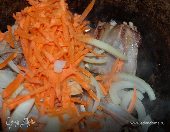 Моем баранину, нарезаем по ребрышку, укладываем в казан. За неимением курдюка, добавила немного растительного масла и начала обжаривать. К зарумянившимся ребрам выкладываю лук полукольцами и натертую на крупной терке морковку, обжариваю, как для плова.