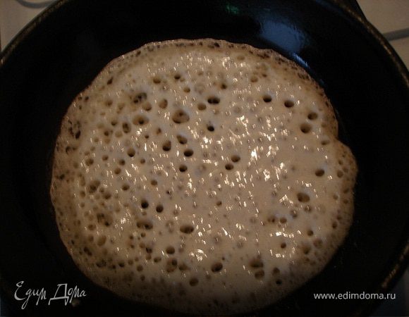 Для того чтобы дрожжевые блины на молоке получились с дырочками, нужно чтобы тесто поднялось еще 2 раза. Отправьте его в теплое место на 20–30 минут. Затем размешайте, снова накройте полотенцем и подождите еще 20 минут. Влейте в тесто немного растительного масла, перемешайте и начинайте печь блины. Если тесто будет слишком густыми, похожим на воздушную пену, можно влить немного горячего молока.