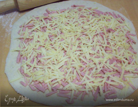 Раскатываем тесто в пласт 5мм, посыпаем натертым сыром и мелко порезанной ветчиной