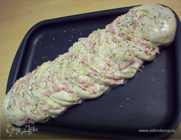 После того как коса увеличилась в двое, смазываем ее яйцом, посыпаем семенами кунжута и ставим выпекаться в духовку