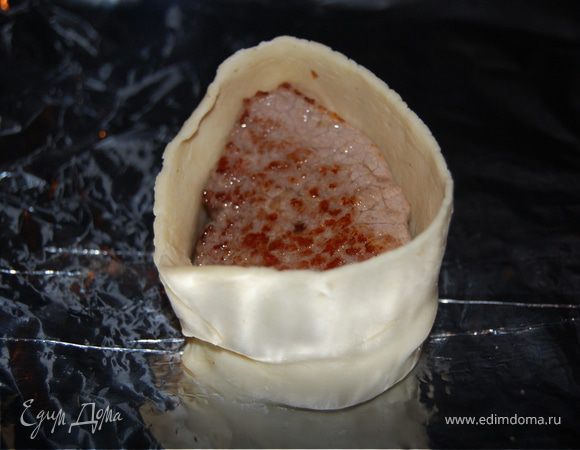 Отрезаем от пласта теста кусок толщиной в 2-3 см и раскатываем в одном направлении в длинную ленку. Сворачиваем тесто и укладываем на противень, в центр получившегося круга кладем нашу говядину и отправляем в разогретую до 180-200 градусов духовку минут на 20, пока тесто не будет готово.