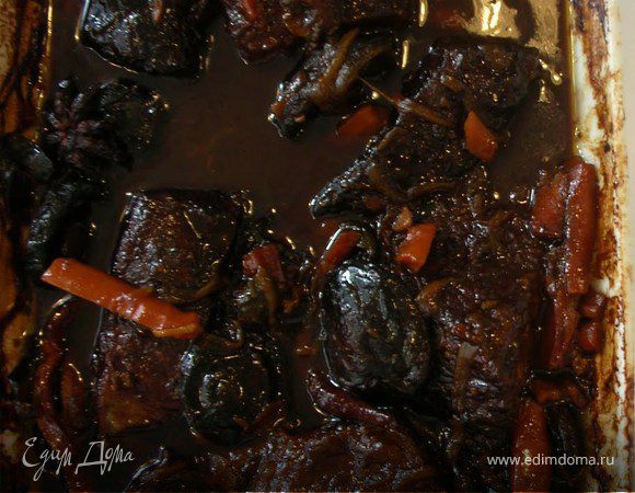 Разогреть духовку до 170 °. Переложить ребра и маринад в чугунную кастрюлю. Добавить куриный бульон и довести до кипения.  Накрыть крышкой и печь течение 1 1 / 2 часа, пока мясо не станет мягким, но не разваливается. Открыть крышку и тушить в течение ещё 45 минут, переворачивая ребра один или два раза, пока соус не убавится примерно на половину и мясо станет очень нежное.