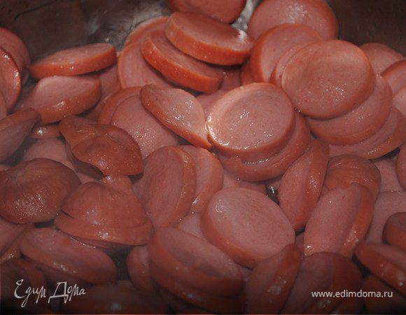 Берем сосиски и нарезаем колечками,кидаем их в разогретую кастрюлю с растит.маслом,обжариваем.После того,как они обжарились,до той степени,что Вам понравилась,добавляем том.пасту и чуть воды,тушим минуток семь.