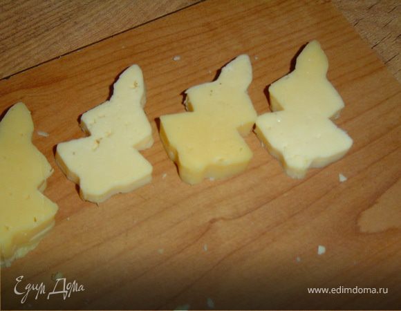 Из сыра вырезаем при помощи формочки (если нет формочки, то можно сделать шаблон, и с его помощью вырезать елочки) елочки.