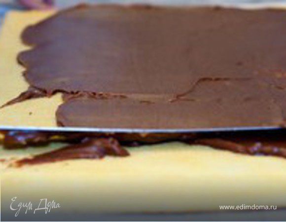 Шоколадный крем:
Масло нарезать ну кусочки и оставить при комнатной температуре. Шоколад измельчить и немного растопить на водяной бане. В небольшой кастрюле доведите до кипения сок маракуйи (если у вас есть свежие плоды, то выдавите из них сок и профильтруйте его).
 
Вылить половину сока в частично растопленный шоколад; вымешать деревянной лопаткой начиная от центра, затем введите еще немного сока, вымешайте крем и добавьте оставшийся сок. 

Добавьте масло, дайте ему немного расплавиться, и вымешайте крем до однородной массы. Поставьте его в холодильник на час/полтора, для того чтобы он приобрел нужную консистенцию. 

Бисквит: 
Достаньте готовый бисквит из духовки, дайте ему остыть и переверните его на другой лист бумаги для выпечки, а первый аккуратно снимите. Пропитайте бисквит сиропом при помощи кисточки.

ДЛя сиропа вскипятите воду с сахаром, дайте сиропу полностью остыть и только потом добавьте в него сок.
Покройте весь бисквит шоколадным кремом. 
Сверните бисквит в рулет, оберните плотно пищевой пленкой и поставьте в холодильник на 6 часов. 
