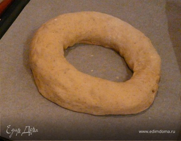 Теперь разделить тесто на 2 части. Раскатать пласт (очень хорошо раскатывается), смазать маслом, посыпать сахаром, изюмом и орехами. Свернуть длинный рулет, сформировать кольцо, выложить на противень на бумагу швом вниз. Взять ножницы и сделать сверху почти до конца надрезы, разворачивая каждый кусок влево и вправо. Накрыть еще на 40 минут.