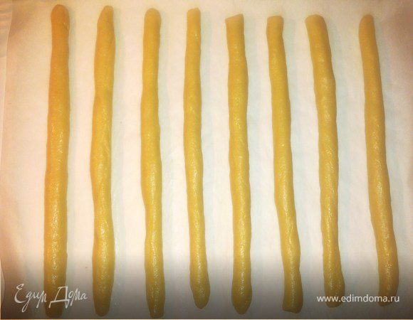 Замесить тесто и положить его в холодильник примерно на три часа (твердое будет удобнее формировать). Скатать палочки 25 см длиной и примерно 1 см в диаметре. Выложить полуфабрикат на противень и пергамент (у меня вместилось по 8 штук сразу). Выпекать 25–30 минут при температуре 180–200°C.