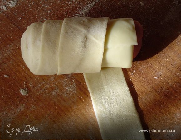 Полосками теста оберните брусочки ветчины с сыром так, чтобы очередной виток закрывал 1 /2 предыдущего. 