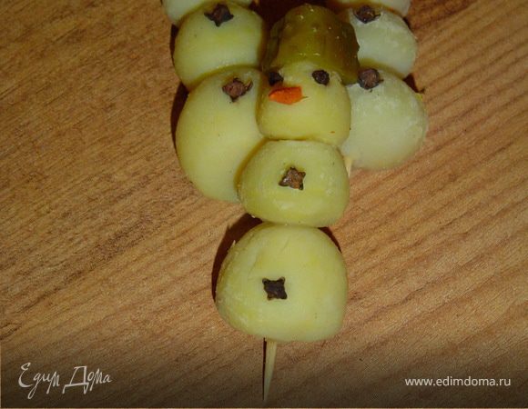 Из отварного картофеля делаем шарики,соединяем их с помощью зубочисток, глазки и пуговки оформляем гвоздикой, нос вырезаем из моркови, ведро - из соленого огурца.Руки делаем из стеблей петрушки.