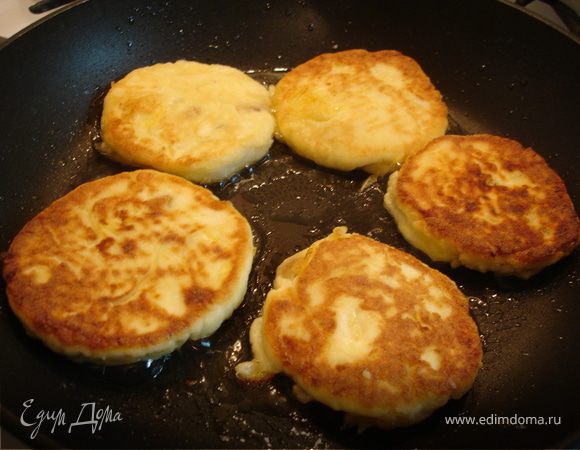 Скатать небольшие шарики из теста, обвалять их в кукурузной муке, сформировать лепёшечки и отпраить на разогретую сковородку с растительным маслом. Жарить на небольшом огне до золотисной корочки, иногда прикрывая крышкой, чтобы сырники хорошо прожарились внутри.