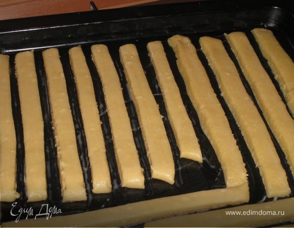 Тесто должно легко раскатываться. Тесто разделить на 2 части и раскатать не очень тонко, пластом приблизительно в 0,5 см. Разрезать на полоски, аккуратно переложить на смазанный маслом противень, смазать яйцом палочки. 
